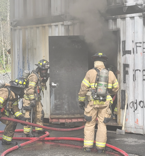 Firefighters getting ready to enter a structure.